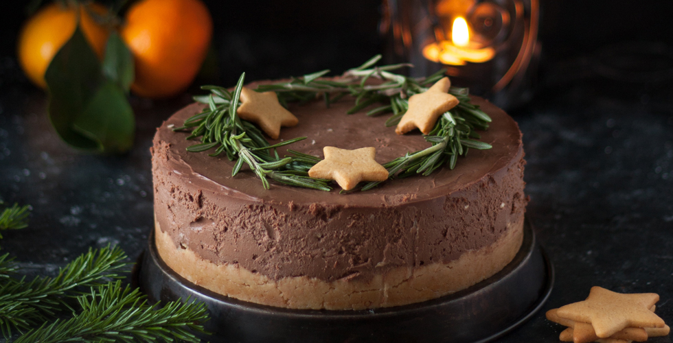 Cheesecake with chocolate, decorated with rosemary and decorated with cookies in the form of stars. Festive Christmas or New Year decoration.